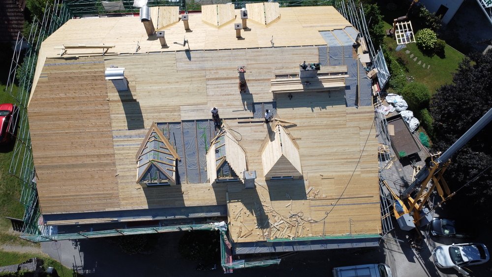 Handwerker auf Dachstuhl eines Mehrparteienhauses im Rohbau bei der Bauleitung in Salzburg